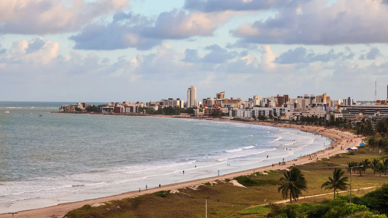 Vista aérea da orla de João Pessoa, com a praia em curva, os edifícios da beira-mar e o oceano